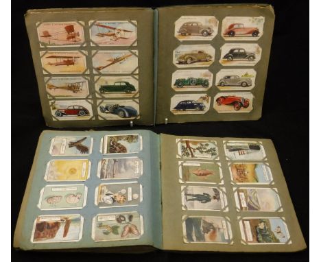 A box containing 14 various cigarette card albums to include Gallaghers, Players, Wills and Ogdens, Churchmans, Cadburys, Lam