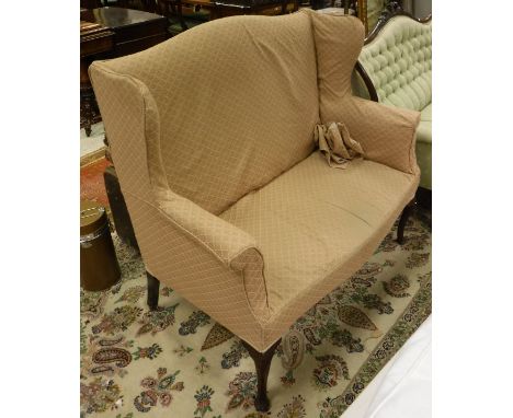 An early 20th Century wing back two seat sofa in pale pink self patterned upholstery, raised on cabriole front legs