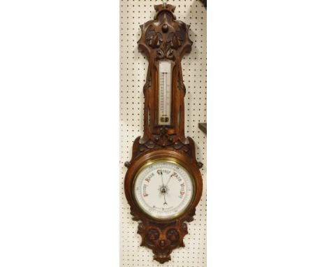A circa 1900 carved oak framed barometer/thermometer with scrolling floral decoration in the Art Nouveau taste