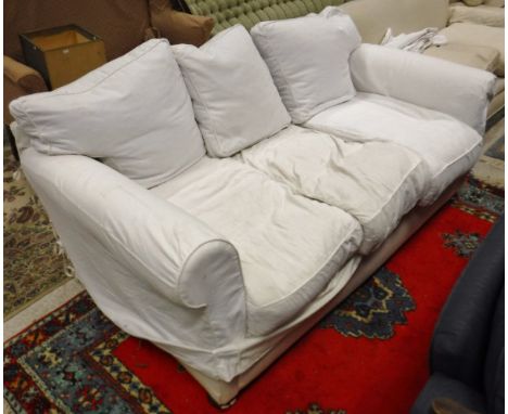 A circa 1900 two seat sofa in plain white loose covers, raised on mahogany bun feet