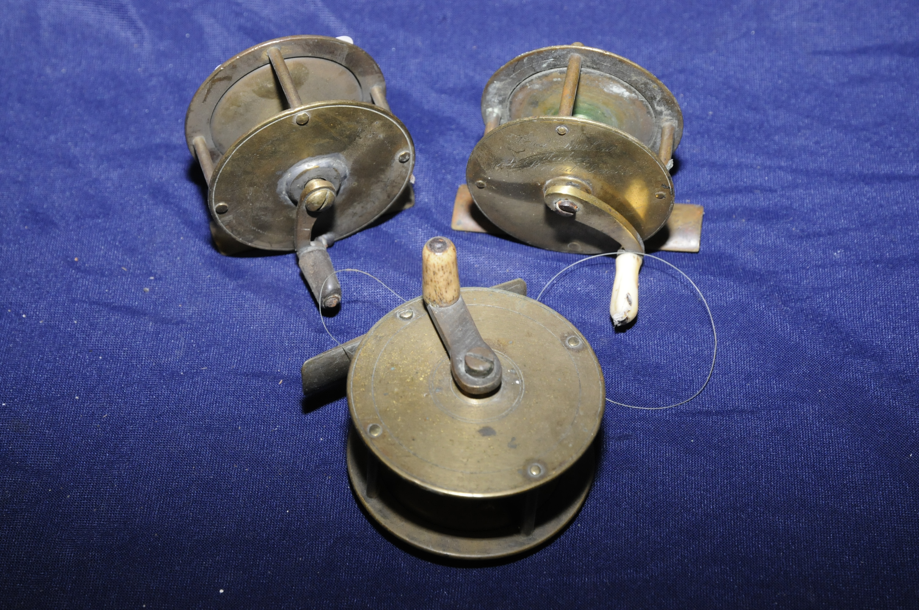 Small vintage brass fishing reel (5.5cm diameter), another similar reel