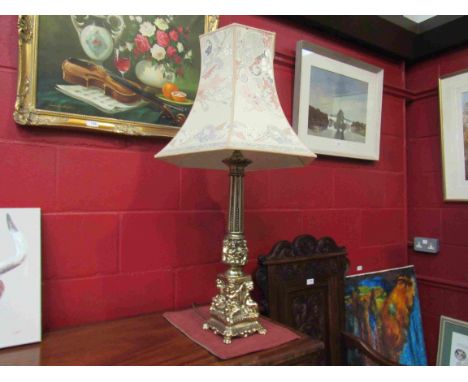 An ornate cherubic design gilt table lamp base with shade