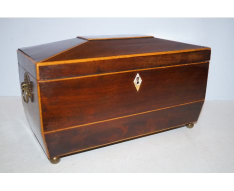 Regency mahogany tea caddy of sarcophagus form, hinged lid enclosing two compartments, loop handles and lozenge shaped escutc