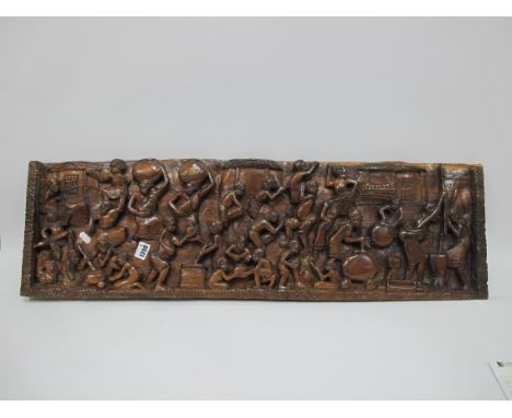 African Hardwood Panel, heavily carved with approximately twenty eight figures in varying poses, 26.5 x 89.5cm.