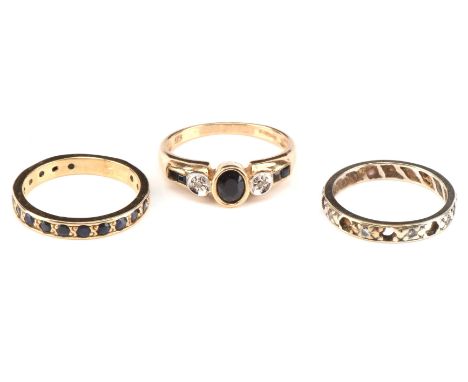 Three gem set rings, including a sapphire and diamond dress ring, set with an oval cut sapphire and square cut sapphires to t