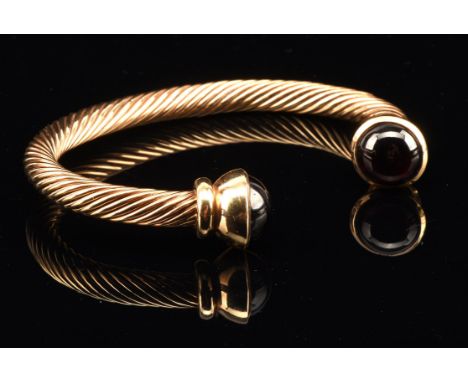 Torque bangle, with twist design and Rubellite terminations, 64mm in diameter, tested as 9 ct, stamped with makers mark Maxwe