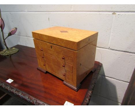 A burr wood jewellery box, the lift lid opening to reveal sectional space, over three graduated front drawers, ogee bracket f