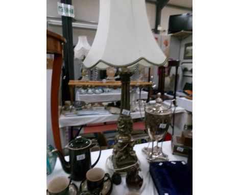 A gilded table lamp with cherubs round base and complete with shade.