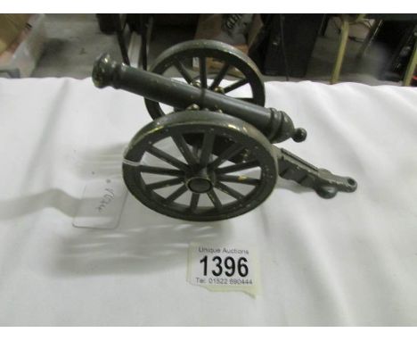 A brass model of a cannon painted green.