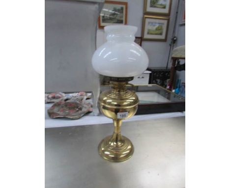 A brass oil lamp with shade and chimney.