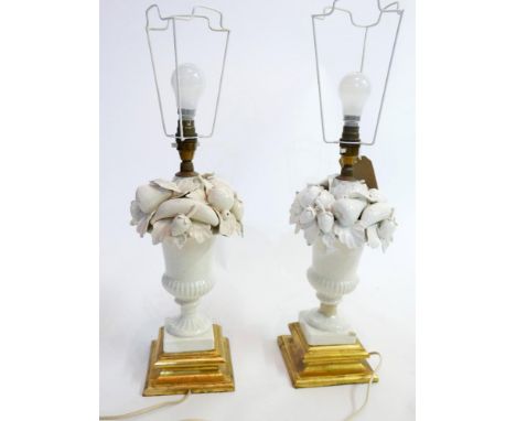 A pair of 20th century white ceramic table lamps in the form of urns of fruit, raised on giltwood bases, H.34cm 