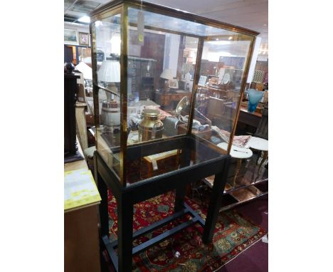 A 20th century brass display case with mirrored base and adjustable glass shelf raised on ebonized stand, H.183 W.94 D.53cm 