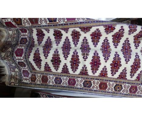 A Kazak carpet with geometric motifs on a cream ground, contained by geometric borders, 233x133cm 