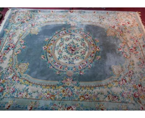 A large 20th century Chinese woollen carpet with central floral medallion on an egg shell blue ground, contained by floral bo