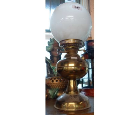 A brass oil lamp with glass chimney and opaque glass globe shade