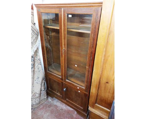 A 92cm vintage oak book cabinet with four adjustable shelves enclosed by a pair of glazed panel doors, set on bracket base
