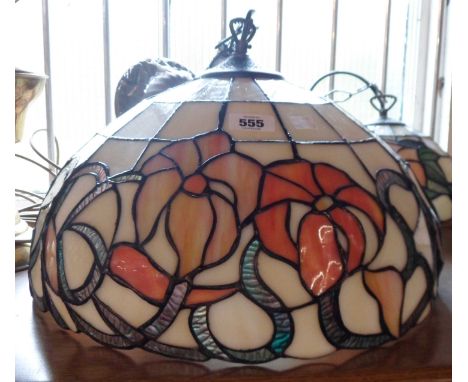 A hanging ceiling light with large Tiffany style stained glass shade depicting stylised flowerheads and trailing foliage
