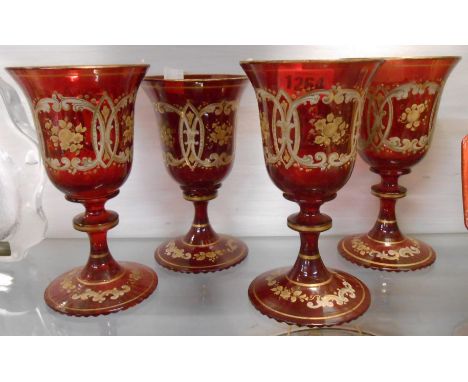 A set of four 19th Century Bohemian ruby glass goblets, each with a bladed knot stem with enamelled and gilt decoration