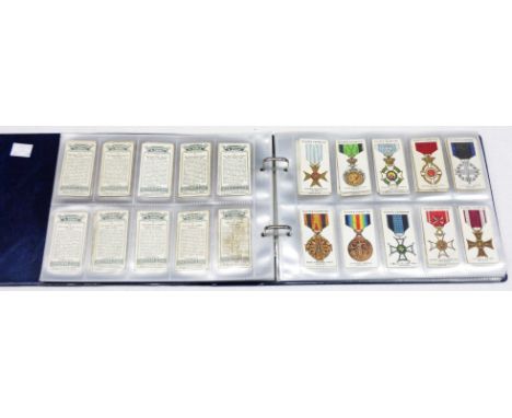 A blue ring bound album containing a collection of sleeve mounted cigarette cards including Players and Wills' examples
