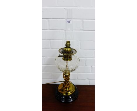 A brass stemmed oil lamp on Corinthian style column with clear glass well and turned black base, 63cm high
