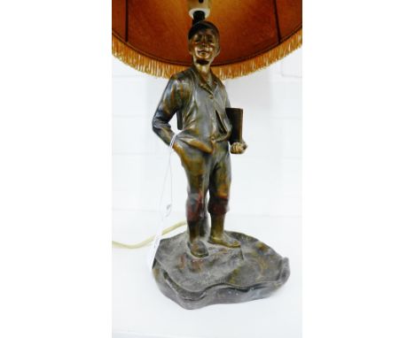 A bronze patinated figural table lamp base of a young boy in a cap with his book under his arms on a circular shaped base, 32