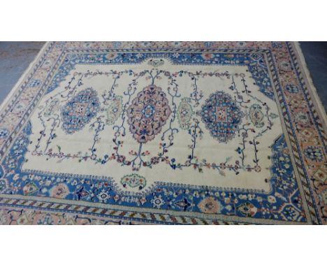 A Tabriz carpet, the cream field with three floral medallions to centre within multiple flowerhead borders in pink and blue, 