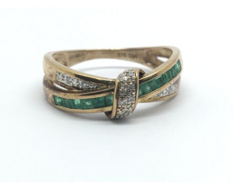 A 9ct yellow gold crossover ring having rows of emeralds and diamonds, ring size approx R