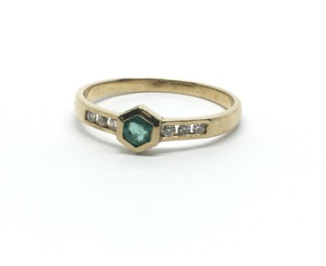 A 14ct yellow gold ring, the central emerald flanked by six diamonds, ring size approx M