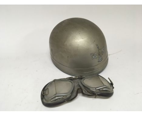 A Vintage Motorcycle crash helmet with transfer badges for The Isle of Man T T race and a pair of Googles