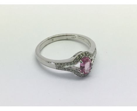 An 18ct white gold ring set with an oval cut pink sapphire and diamond ring with split diamond shoulders, pink sapphire appro