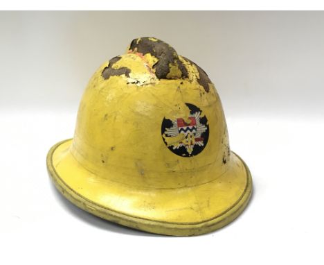 A vintage cork fireman’s helmet in painted yellow and printed emblem