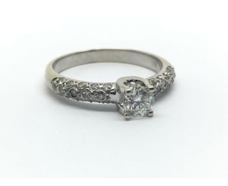 An 18ct white gold and diamond solitaire ring, the single central approx 0.33ct diamond flanked by diamond shoulders, ring si