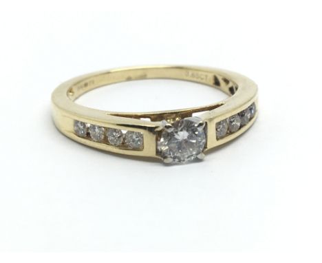 An 18ct yellow gold ring, the central diamond solitaire flanked by eight smaller diamond, approx 0.65ct, ring size approx R
