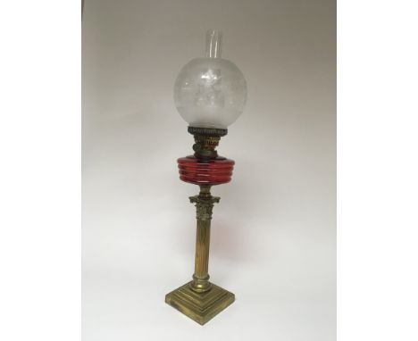A Quality late 19th century brass corinthian column oil lamp with a cranberry glass reservoir and acid etched shade. Height 7