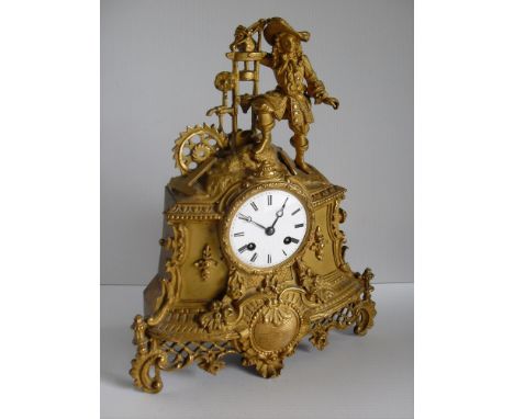 A 19th century French gilt mantle clock surmounted by an applied figurine, circular dial (glass missing), Roman numerals with