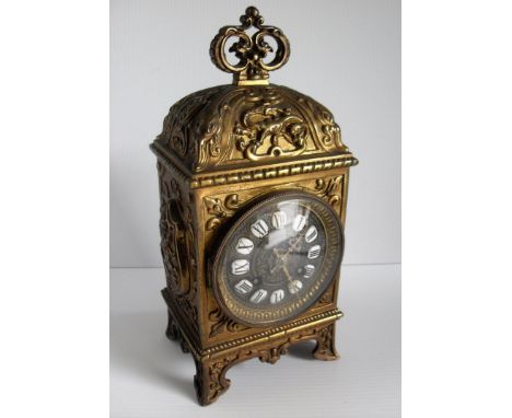 A 19th century French table clock with elaborately carved brass case, Roman numerals on porcelain (one loose), mechanism by R