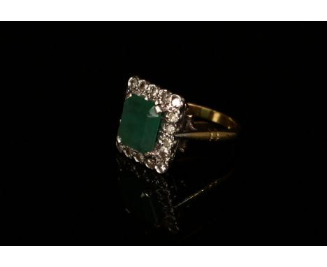 An Art Deco style diamond and emeral ring, central rectangular stone claw set within eighteen round brilliant cut diamonds, p