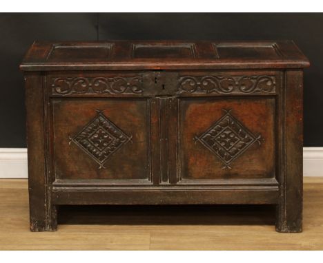 An early 18th century oak blanket chest, hinged top above a frieze carved with scrolling leaves in the Gothic tracery manner,