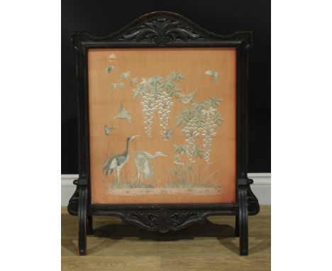 A late Victorian oak fire screen, the glazed banner with a Chinese silk panel worked on a peach ground with cranes, song bird