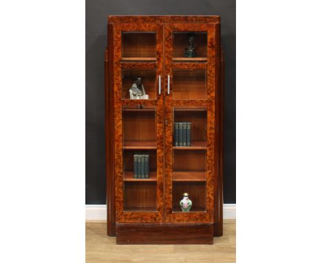 An Art Deco walnut bookcase or display cabinet, caddy top above a pair of bevelled glazed doors enclosing four adjustable she