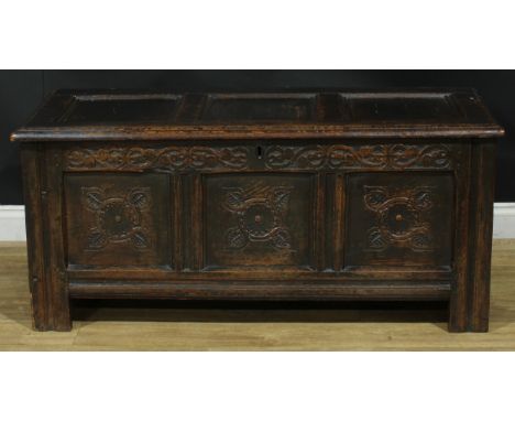 A late 17th/early 18th century oak blanket chest, hinged top above a three panel front carved with stylised flowers and leave