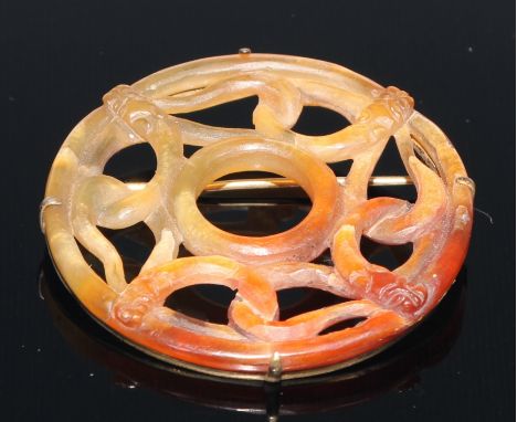 A Chinese Celadon and Russet Jade circular panel, the central ring within a broad band of four intertwined snake like beasts,