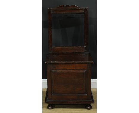 An 18th century mahogany box chair, rectangular back, hinged seat above a raised and fielded panel, skirted base, turned fore