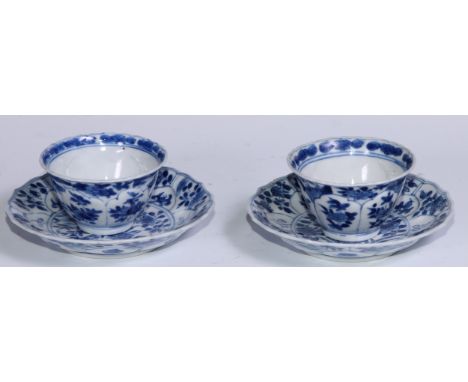 A pair of Chinese wine cups or tea bowls and saucers, painted in tones of underglaze blue with flowers and leafy sprigs withi