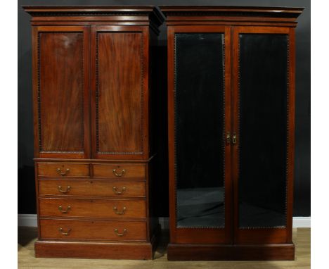 A George III Revival mahogany two-piece bedroom suite, comprising linen press and wardrobe, the linen press with a pair of pa