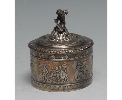 An early 20th century German silver cylindrical table snuff box, the domed cover surmounted with a revelling putto within a b