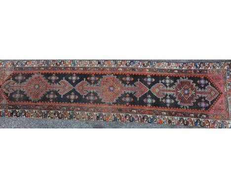 A Middle Eastern wool runner rug, rectangular field worked with hooked medallions, banded borders with stylised animals, 348c