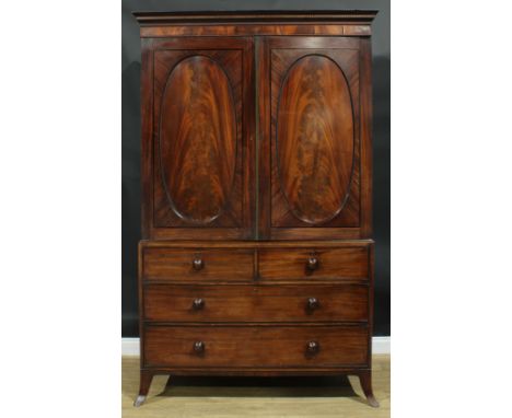 A George III mahogany linen press, moulded parcel-parquetry cornice above a pair of oval flame veneered panel doors enclosing