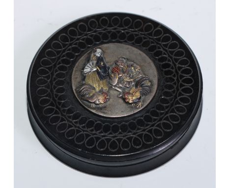 A 19th century lignum vitae circular snuff box, engine turned and applied with a Japanese moxed metal roundel, 7.5cm diam 