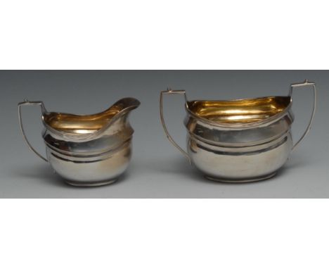 A George III style silver boat shaped cream jug and sugar basin, angular scroll handles, gilt interiors, the latter 17cm wide
